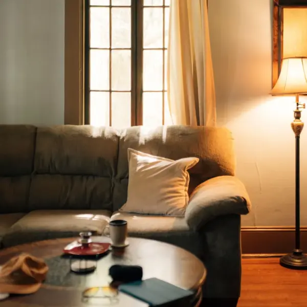 A warm, inviting living room interior featuring a sofa, coffee table, and floor lamp giving a peaceful home vibe