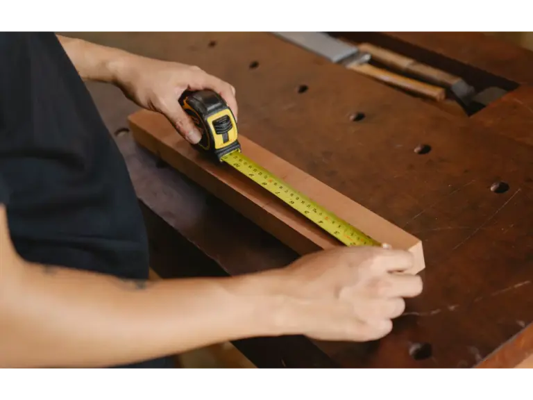 A craftsman measuring a wooden plank on a workbench, focusing on precision and skill while tackling hands‑on DIY Projects with confidence.