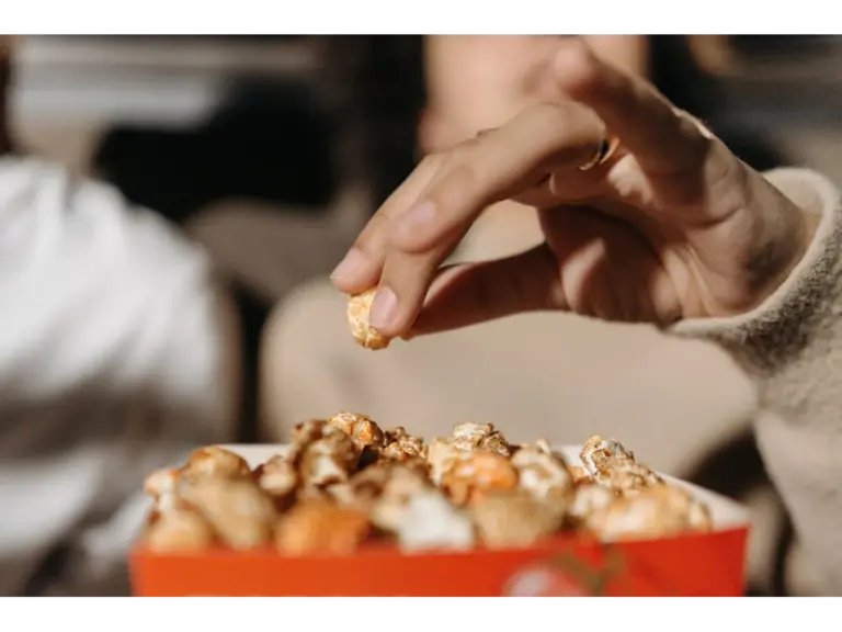 A hand reaches for a piece of popcorn in a backyard movie setting, creating a cozy atmosphere