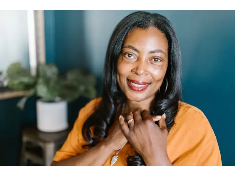 Beautiful portrait of a smiling African American woman embracing empowering beauty while wearing an orange top, indoors.