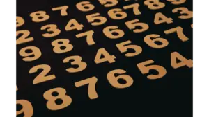 Close-up view of wooden numbers arranged on a black surface, subtly echoing dream numbers and their mysterious nighttime symbolism.
