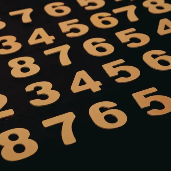 Close-up view of wooden numbers arranged on a black surface, subtly echoing dream numbers and their mysterious nighttime symbolism.