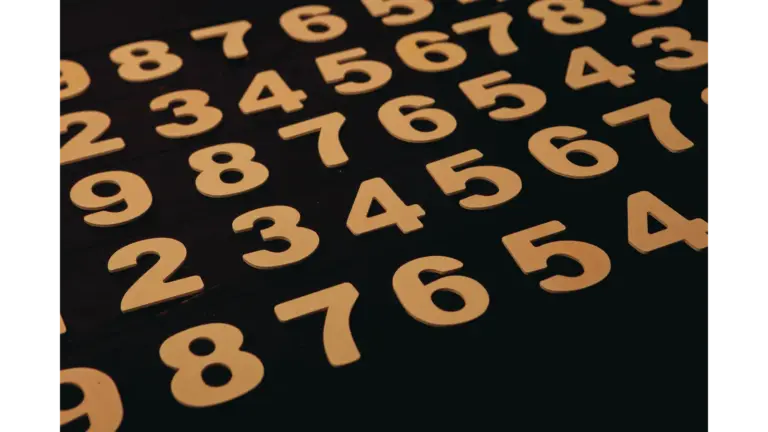 Close-up view of wooden numbers arranged on a black surface, subtly echoing dream numbers and their mysterious nighttime symbolism.
