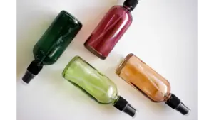Four colorful spray bottles arranged on a white surface, perfect for showcasing DIY room sprays and fresh, cozy home fragrance ideas