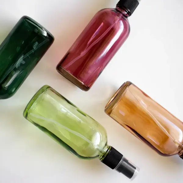 Four colorful spray bottles arranged on a white surface, perfect for showcasing DIY room sprays and fresh, cozy home fragrance ideas