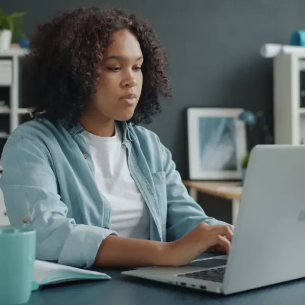 Young woman focused on remote work at her home office desk with a laptop, fully locked into the energy of the remote boom.