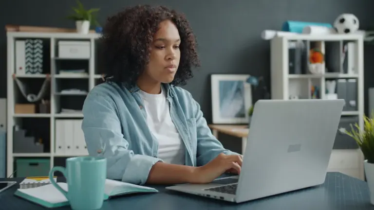 Young woman focused on remote work at her home office desk with a laptop, fully locked into the energy of the remote boom.
