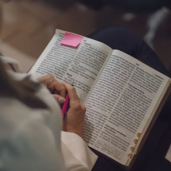 In Friday's daily devotional, a woman reads the Bible with a pink sticky note attached.