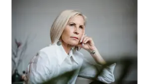 Portrait of a well-dressed senior woman embracing empowering beauty, lost in pensive thought indoors.