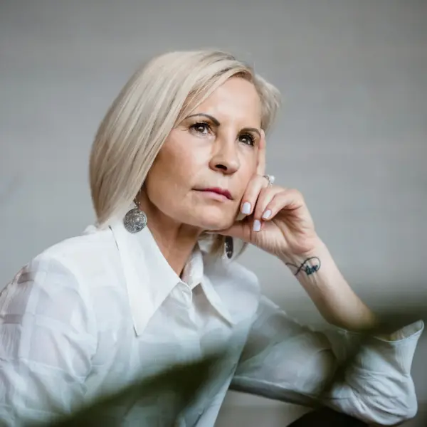 Portrait of a well-dressed senior woman embracing empowering beauty, lost in pensive thought indoors.