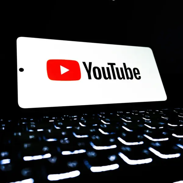A glowing YouTube logo displayed above a dark, illuminated keyboard, symbolizing the digital world of chaos content and longform storytelling trends.