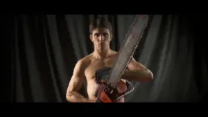 Music videos for "This Must Be The Place (Cover)," featuring Miles Fisher as a shirtless man holding a chainsaw, posing against a dark backdrop.