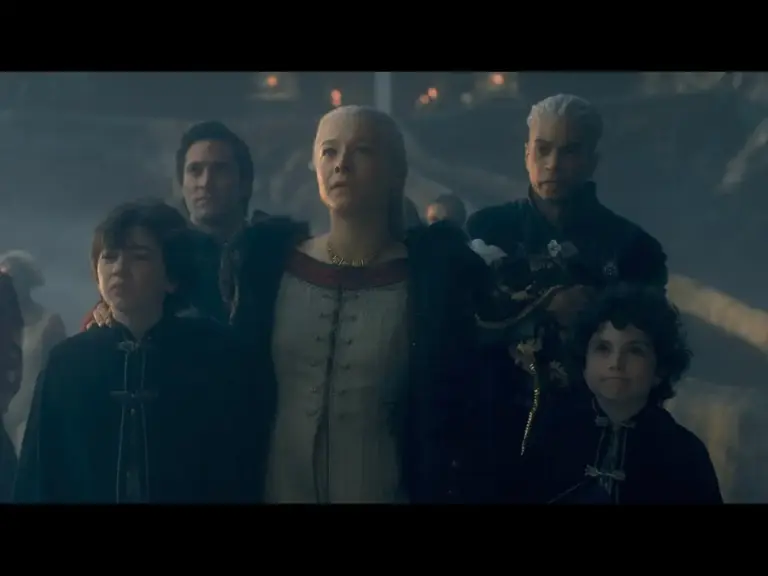 A group of people walking together, with a woman in a historical dress leading, followed by three boys and a man behind her. The background appears misty and atmospheric.