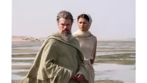 Matt Damon and Zendaya in Christopher Nolan's The Odyssey (2026) in a desolate landscape with shallow water.