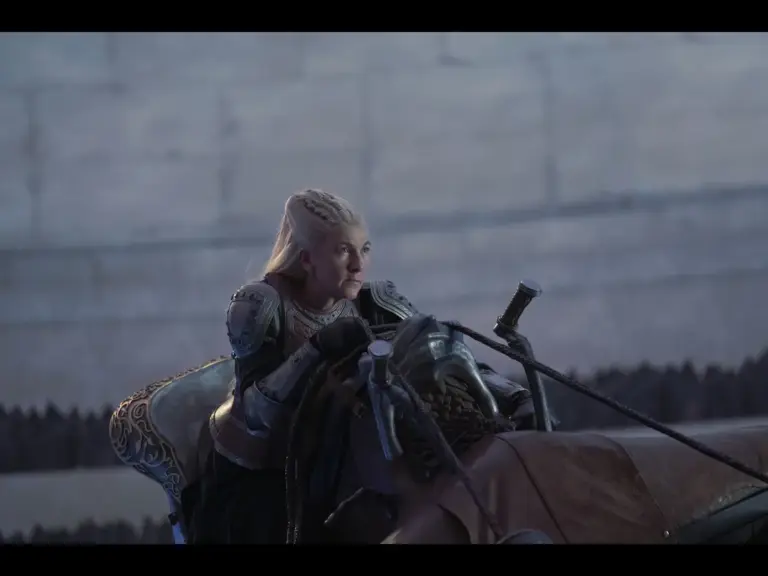 A character in armor riding a steed with a focused expression, set against a blurred backdrop.