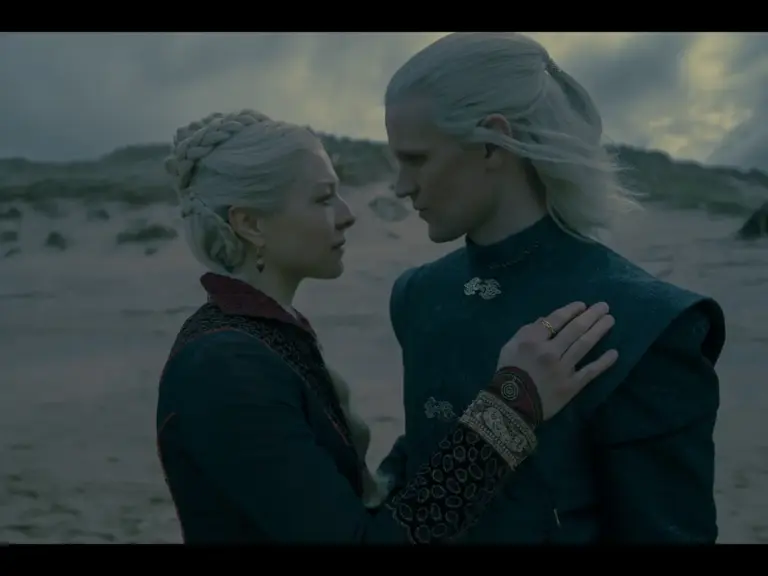 Matt Smith and Emma D'Arcy in House of the Dragon (2022) standing closely together on a beach, their faces conveying a deep emotional connection.