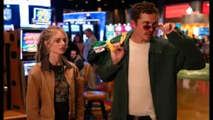 Samara Weaving and Karl Glusman are captured standing in front of a bustling casino, with colorful lights illuminating the scene in Eenie Meanie