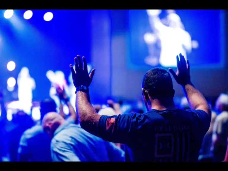In Tuesday's daily devotional, a man in a church setting lifts his hands in praise, revealing his freedom in the Lord.