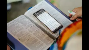 In Thursday's daily devotional, a study area with an open Bible and phone is prepared for someone.