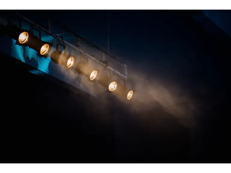 Moody stage lighting with a smoke effect to add atmospheric drama, enhanced by subtle set hauntings in the shadows.