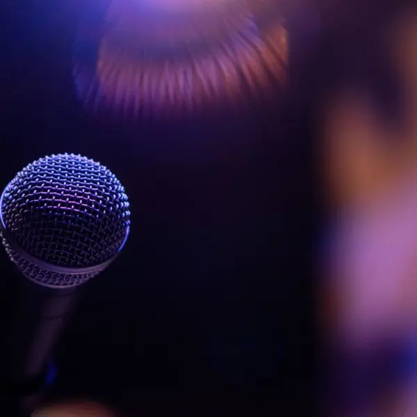 A dramatic close-up of a microphone under a spotlight, evoking performance, music vibes, and music drama