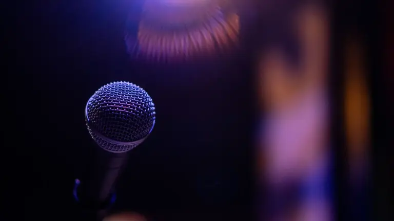A dramatic close-up of a microphone under a spotlight, evoking performance, music vibes, and music drama
