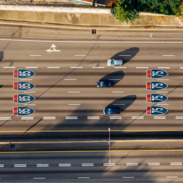 Overhead view of cars on Atlanta’s I‑85 and I‑75 highways on a sunny day, highlighting busy travel patterns influenced by changing gas prices.