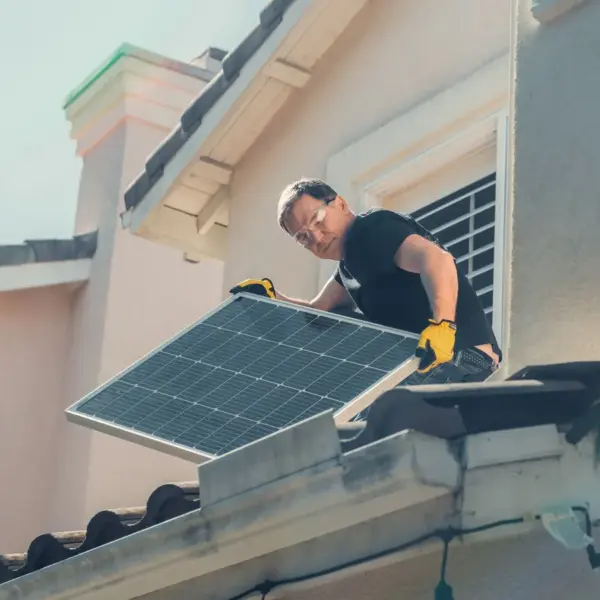 A technician in protective gear installs solar panels on a house roof, promoting sustainability and reflecting the growing housing trends pushing buyers toward smarter, energy‑efficient homes.
