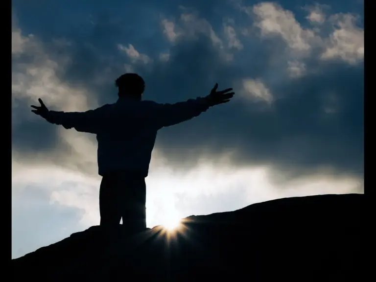 In Friday's daily devotional, a man stands with arms outstretched at sunrise, giving praise for life.