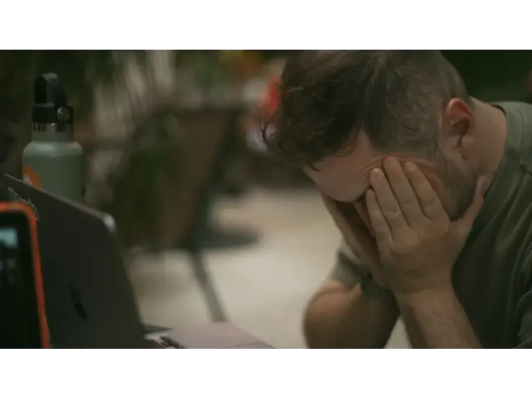 Adult male appears stressed, sitting indoors with his hands on his face, reflecting the intense emotional pressure often the result of fire dreams.