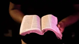 In Thursday's daily devotional, a man holds an open Bible in front of him to read Scripture.