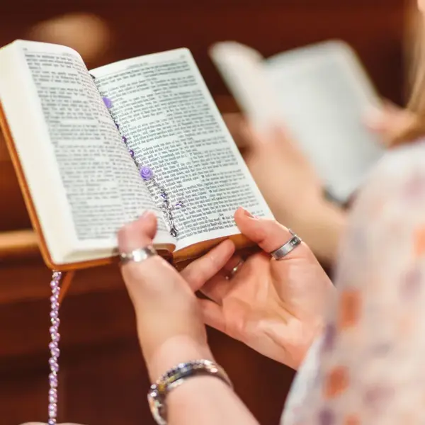 In today's daily devotional, a woman sits on a church pew and reads Scripture.