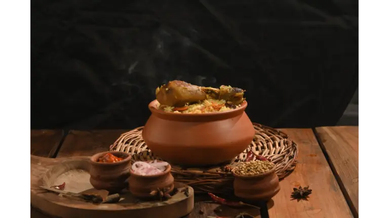 A steaming clay pot filled with rice and chicken sits on a wooden table surrounded by spices and small earthen bowls, capturing the rustic essence of ancient food and traditional cooking.