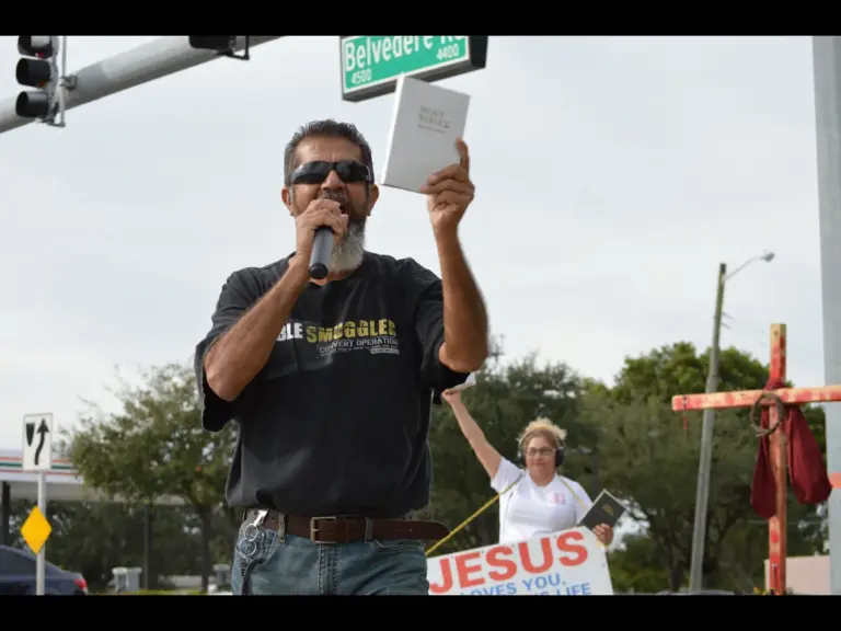 In Thursday's daily devotional, a man preaches the gospel to a crowd while holding up his Bible.