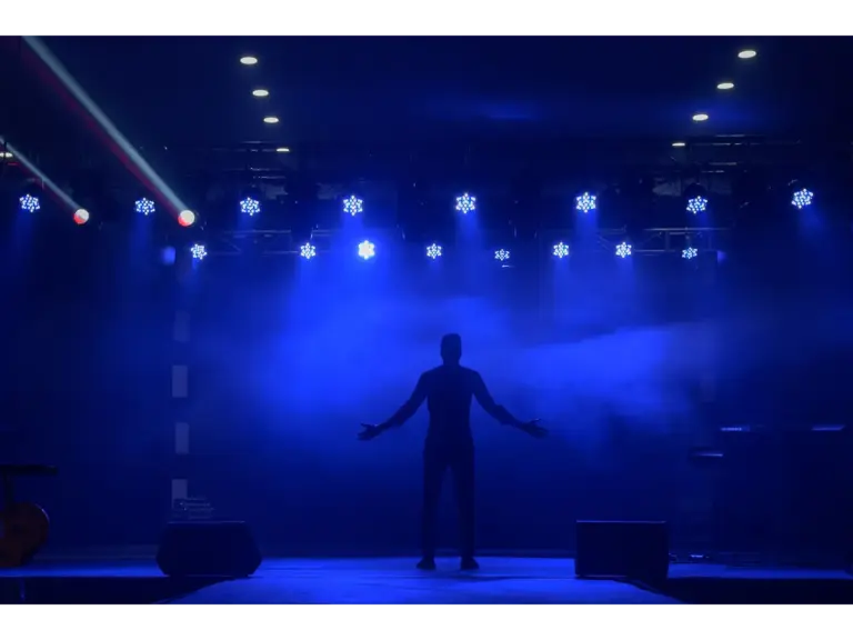 A dramatic scene of a silhouette standing on stage with vibrant blue lighting, offering great copy space and music drama