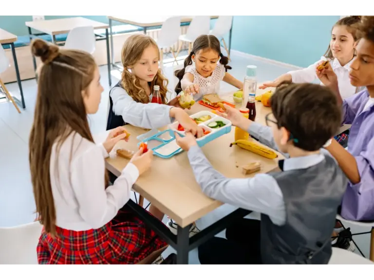 Group of diverse children having lunch in a school canteen, sharing and enjoying healthy snacks as part of their daily school lunches.