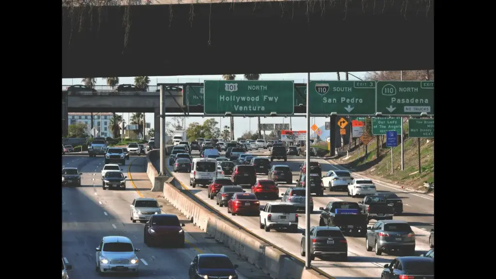 A busy highway with multiple vehicles and road signs indicating directions to Hollywood Freeway, Ventura, San Pedro, and Pasadena. traffic, road trip, travel