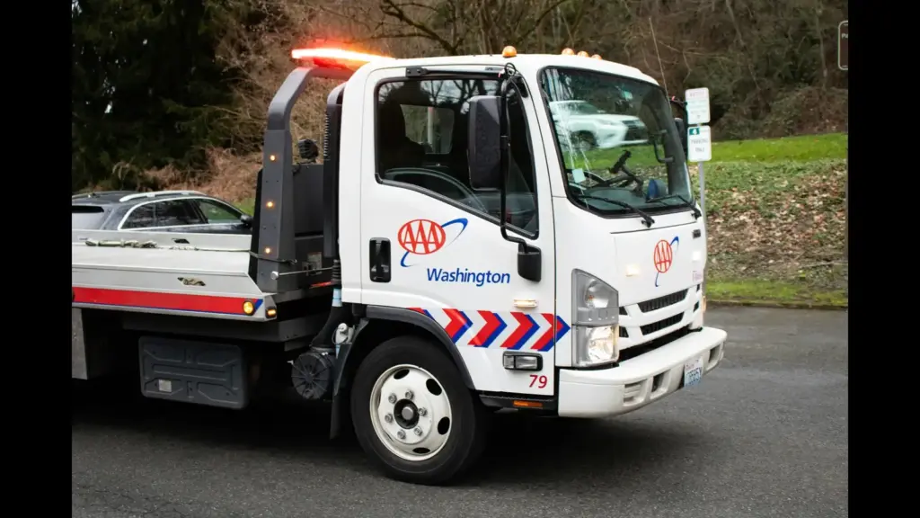 A AAA Washington tow truck parked on a road with trees and grass in the background. Roadside assistance, road trip safety