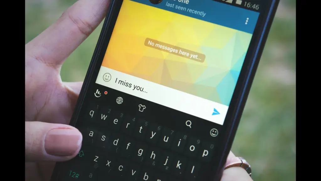 A close-up of a smartphone displaying a messaging app with a text input field that reads "I miss you..." and a background that shows "No messages here yet..." texting boundaries, text messaging, relationships