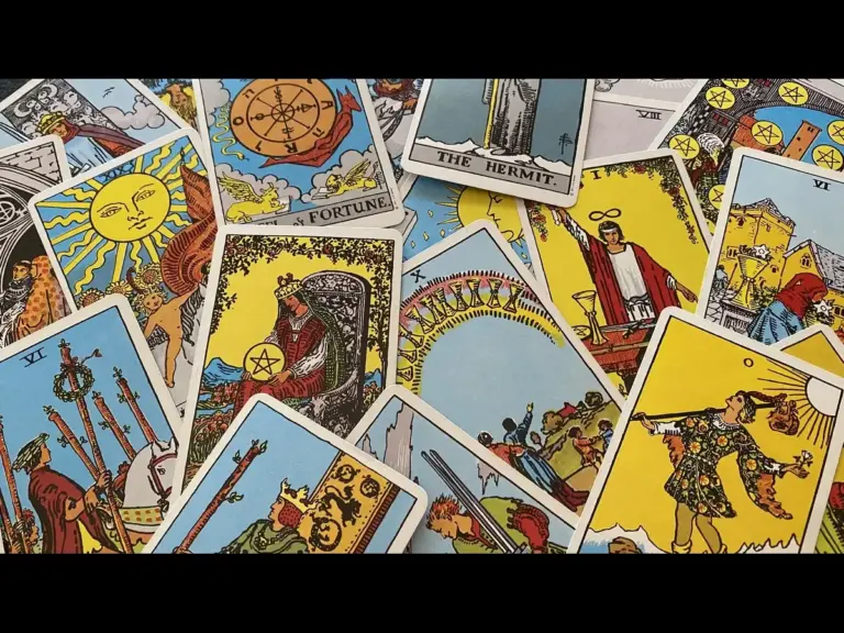 A collection of tarot cards spread out on a surface, featuring various illustrations including symbols like the sun, fortune, and figures such as the hermit. Rider-waite