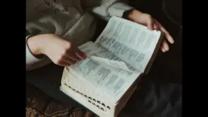 In daily devotional, a person studies the open Bible, which is placed on their lap.