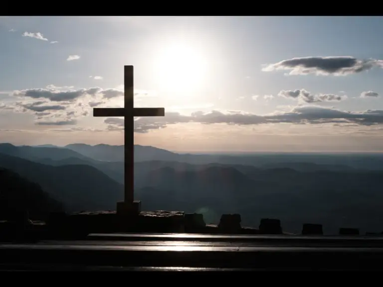 In Monday's daily devotional, a cross is seen against a quiet ocean background with beautiful hues.