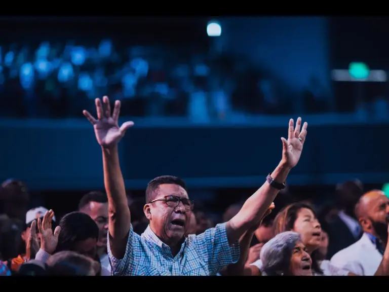 In Wednesday's daily devotional, a man is shown lifting his hands high in a worhip service at church, surrounded by other worshippers.