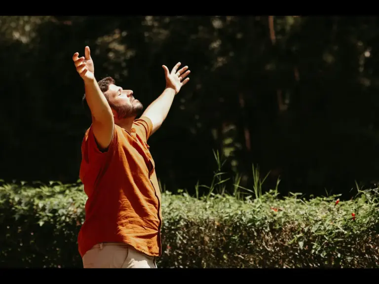 In Monday's daily devotional, a man stands outside and lifts his arms as in casting his care upon the Lord.