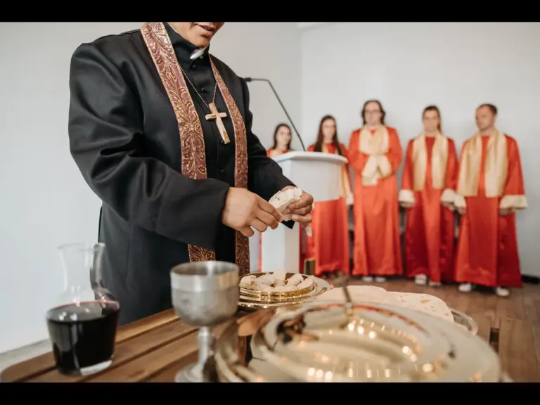 In Friday's daily devotional, a minister serves communion to her congregation with the choir in the background.