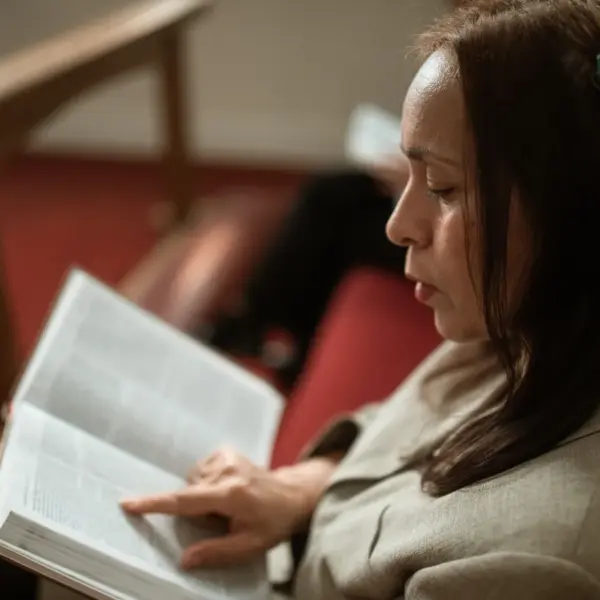 In daily devotional, a woman sits quietly and reads the Bible in a church setting.