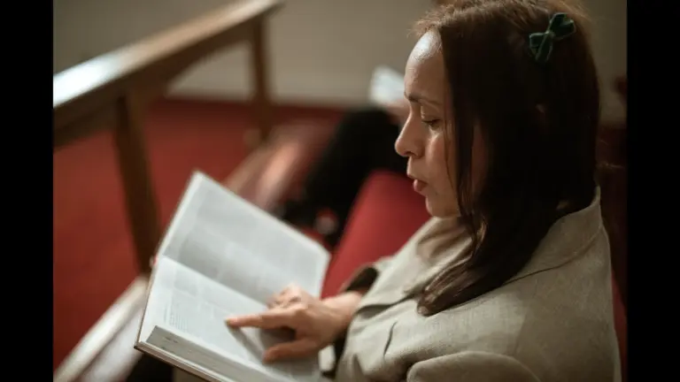 In daily devotional, a woman sits quietly and reads the Bible in a church setting.