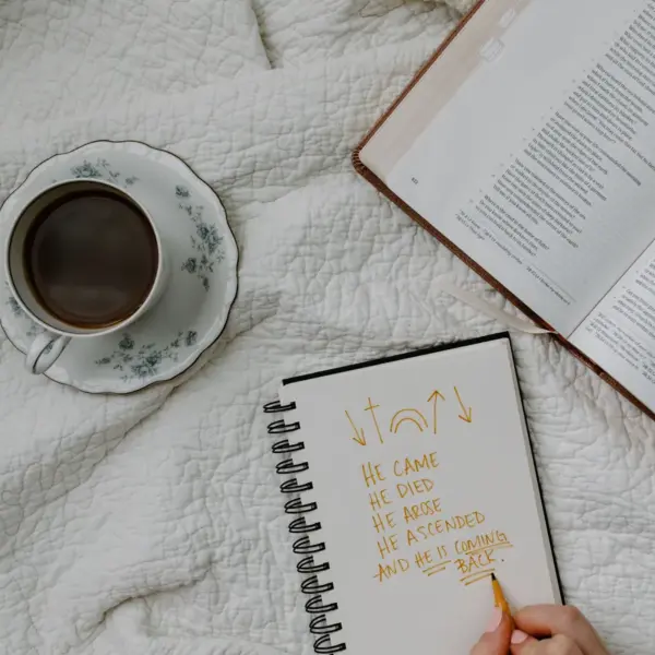 In Monday's daily devotional, a person studies the Bible with coffed and notepad close.