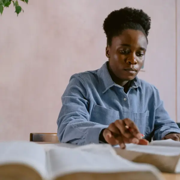 In Friday's daily devotional, a woman sits at a table studying the Bible.