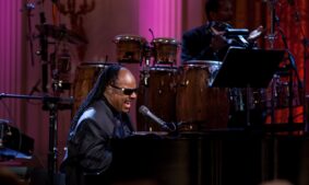 Stevie Wonder, whose Songs in the Key of Life turns 50, sings at a piano during a White House performance